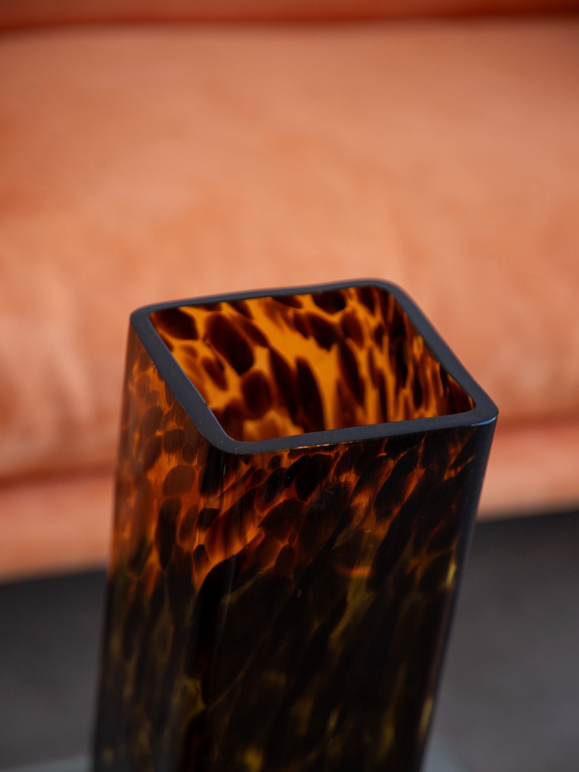 Close-up of Italian vintage Murano-style glass vase showcasing tortoiseshell pattern and smooth rim against a peach-toned background