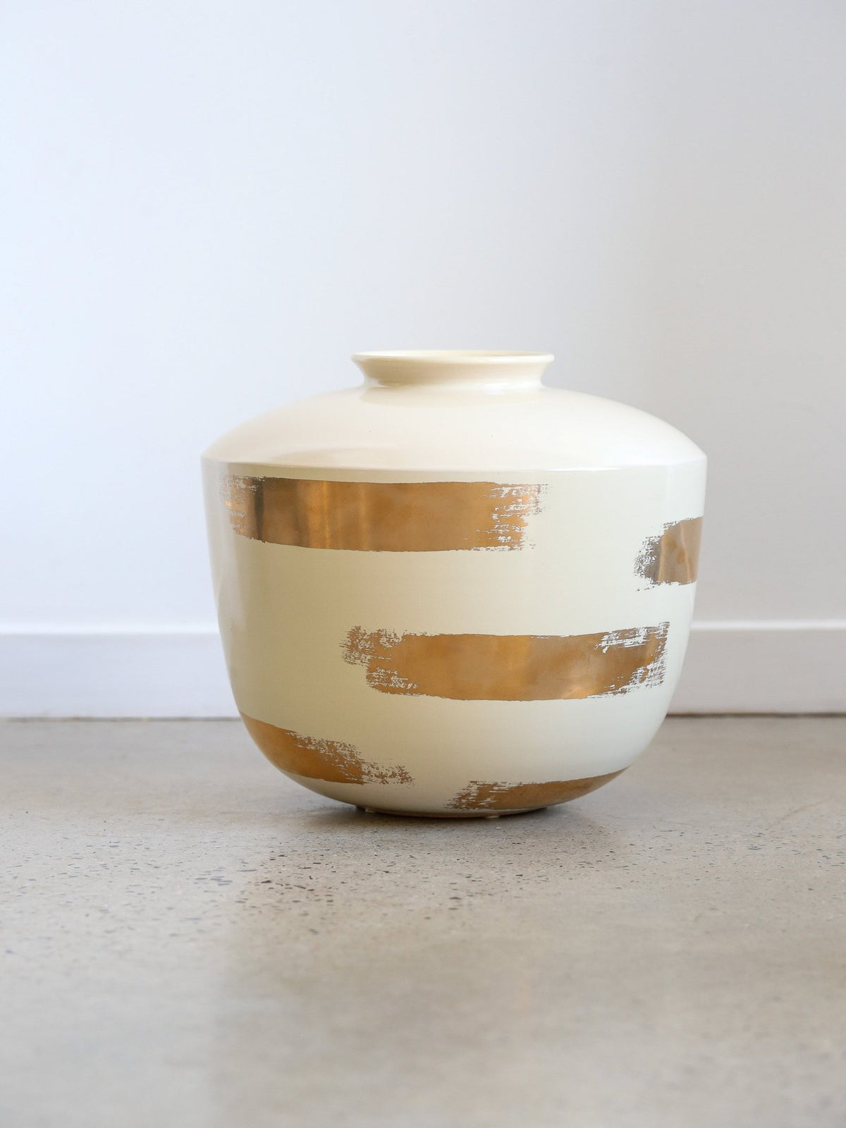 White vase with gold stripes on a light surface