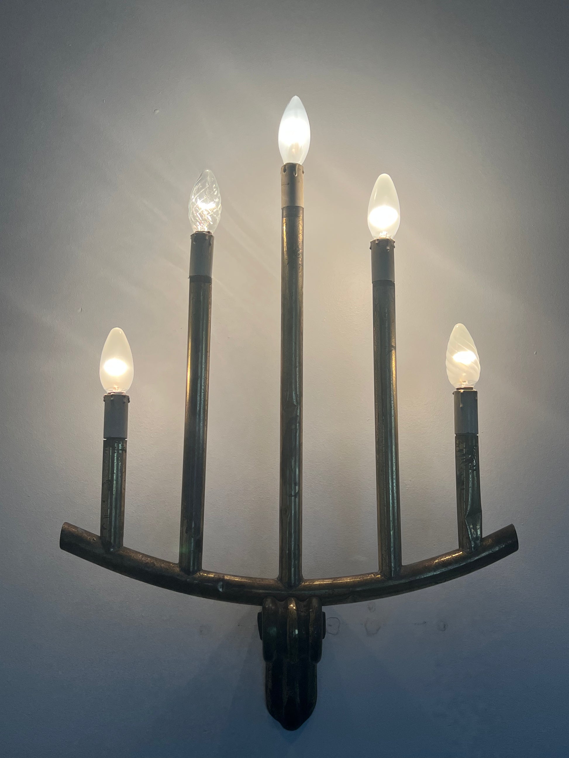 lit wall light with five bulbs over a white background