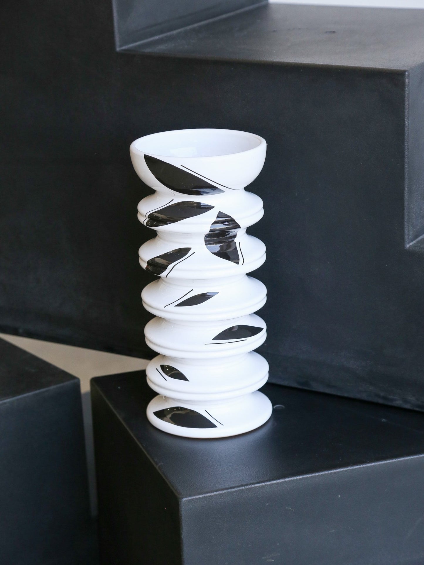 White spiral vase on a black pedestal with a black background