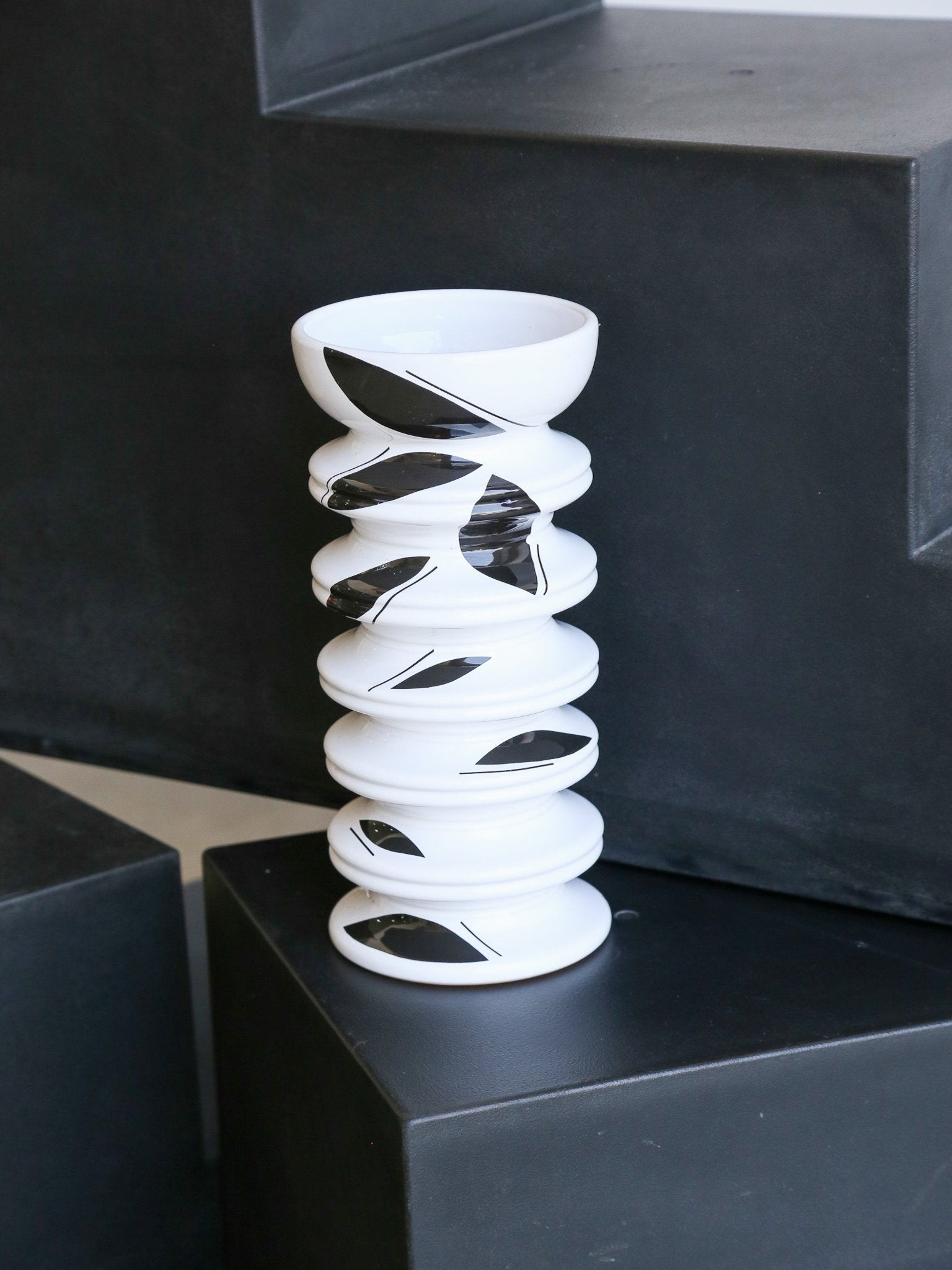 White spiral vase on a black pedestal with a black background