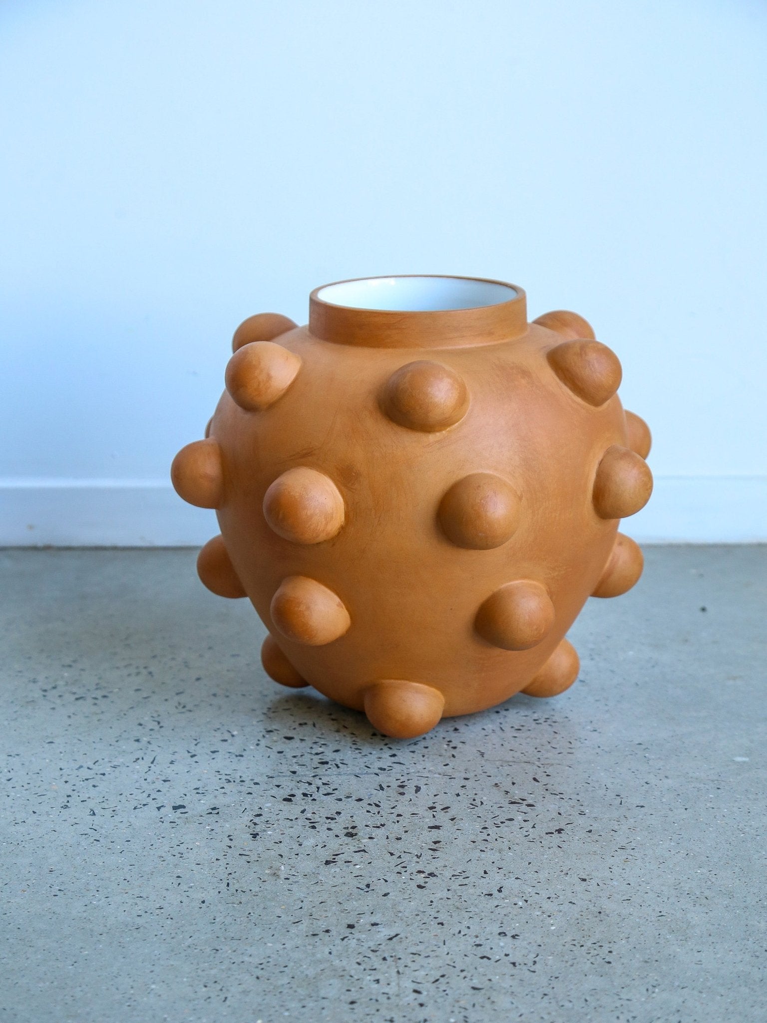Brown textured vase on a gray surface with a light blue background