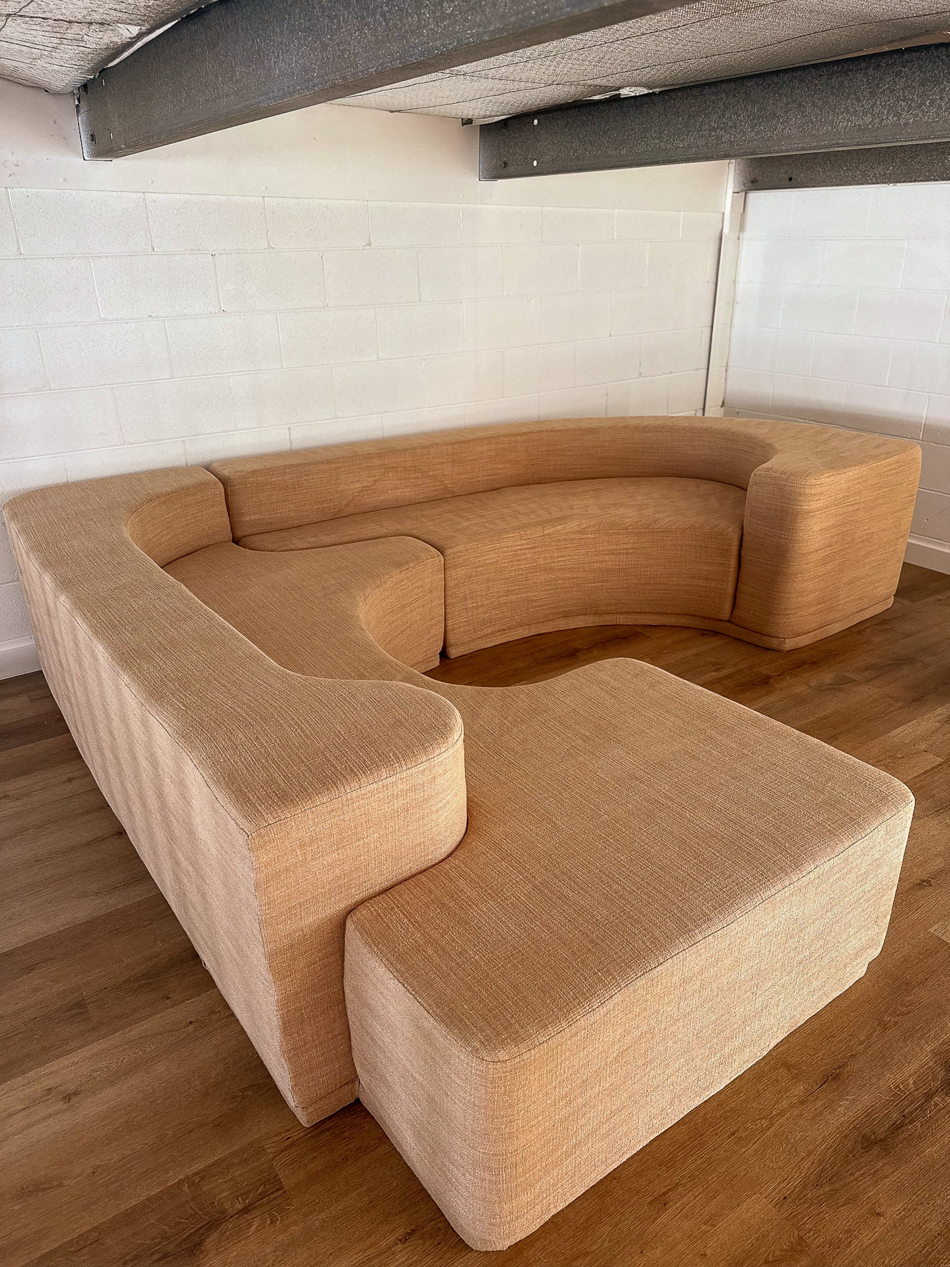 Beige sectional sofa on a wooden floor with a white wall background