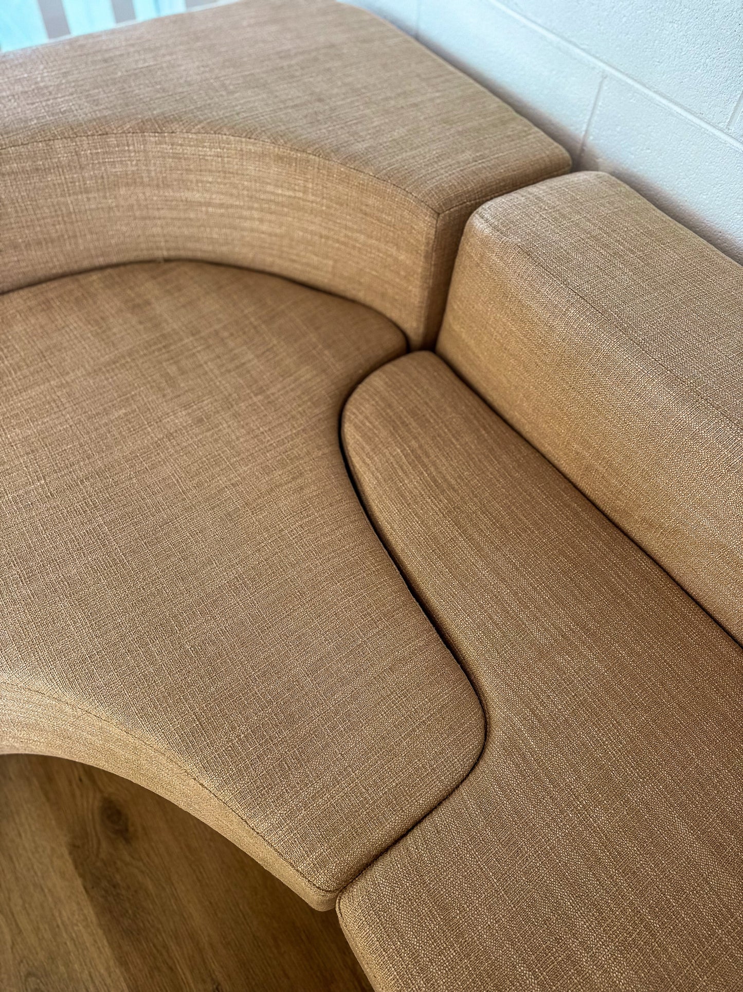 Beige curved sofa in a room with white walls.