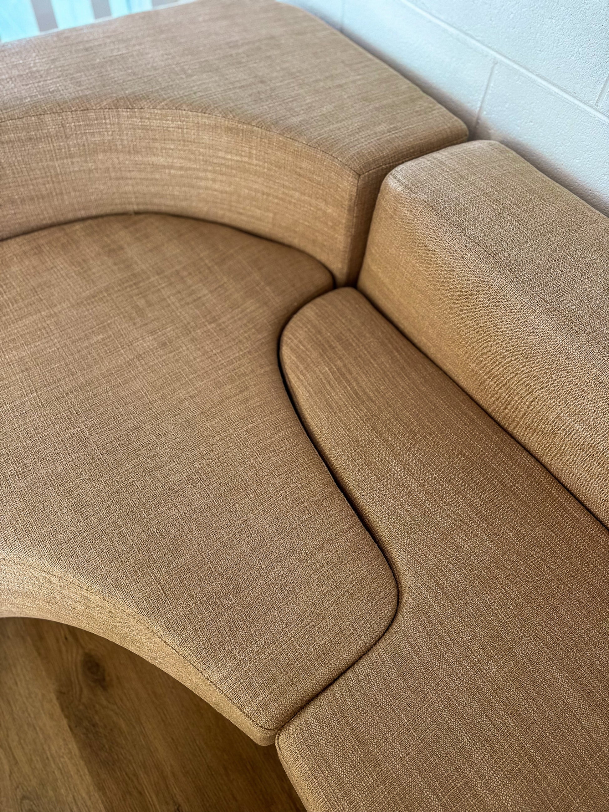 Beige curved sofa in a room with white walls.