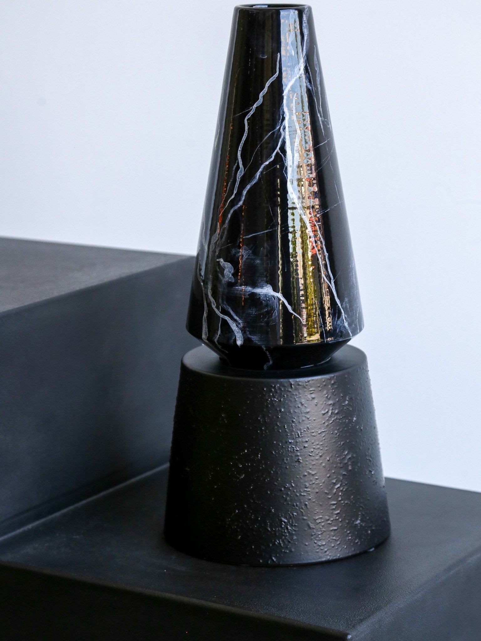 Decorative black vase with marble-like patterns on a gray surface