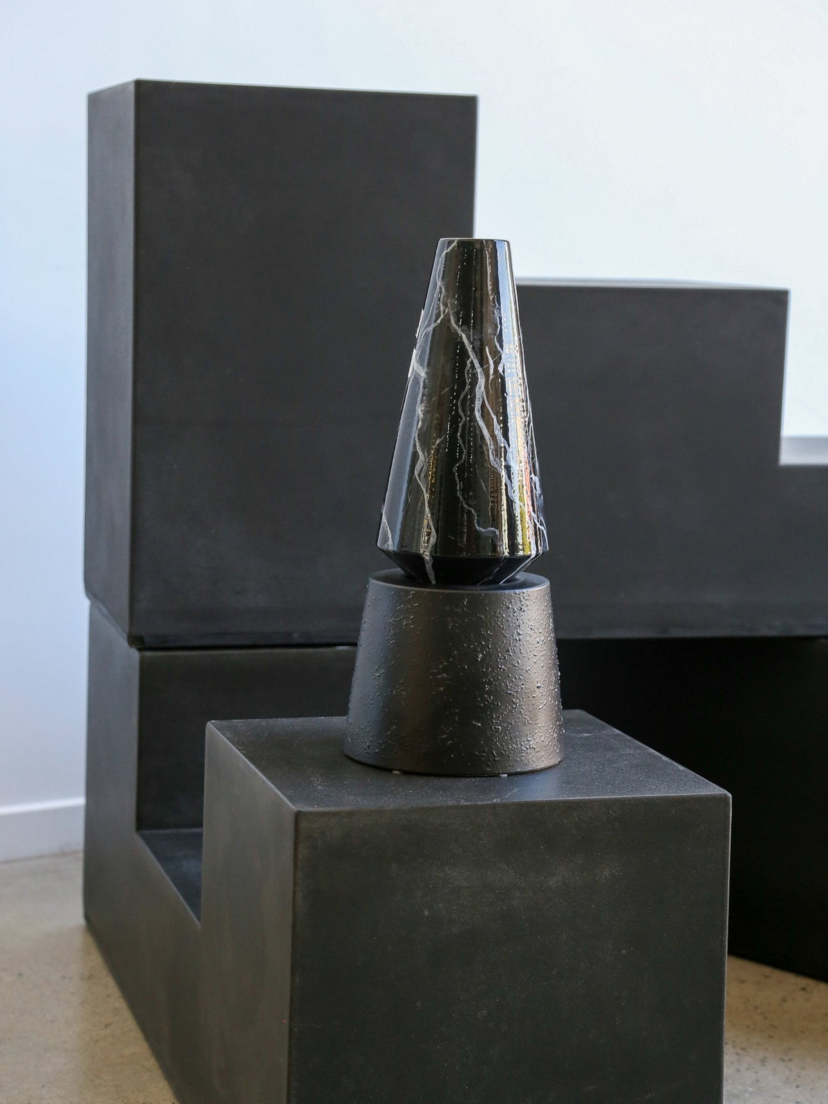 Dark stone sculpture on a pedestal with a plain background
