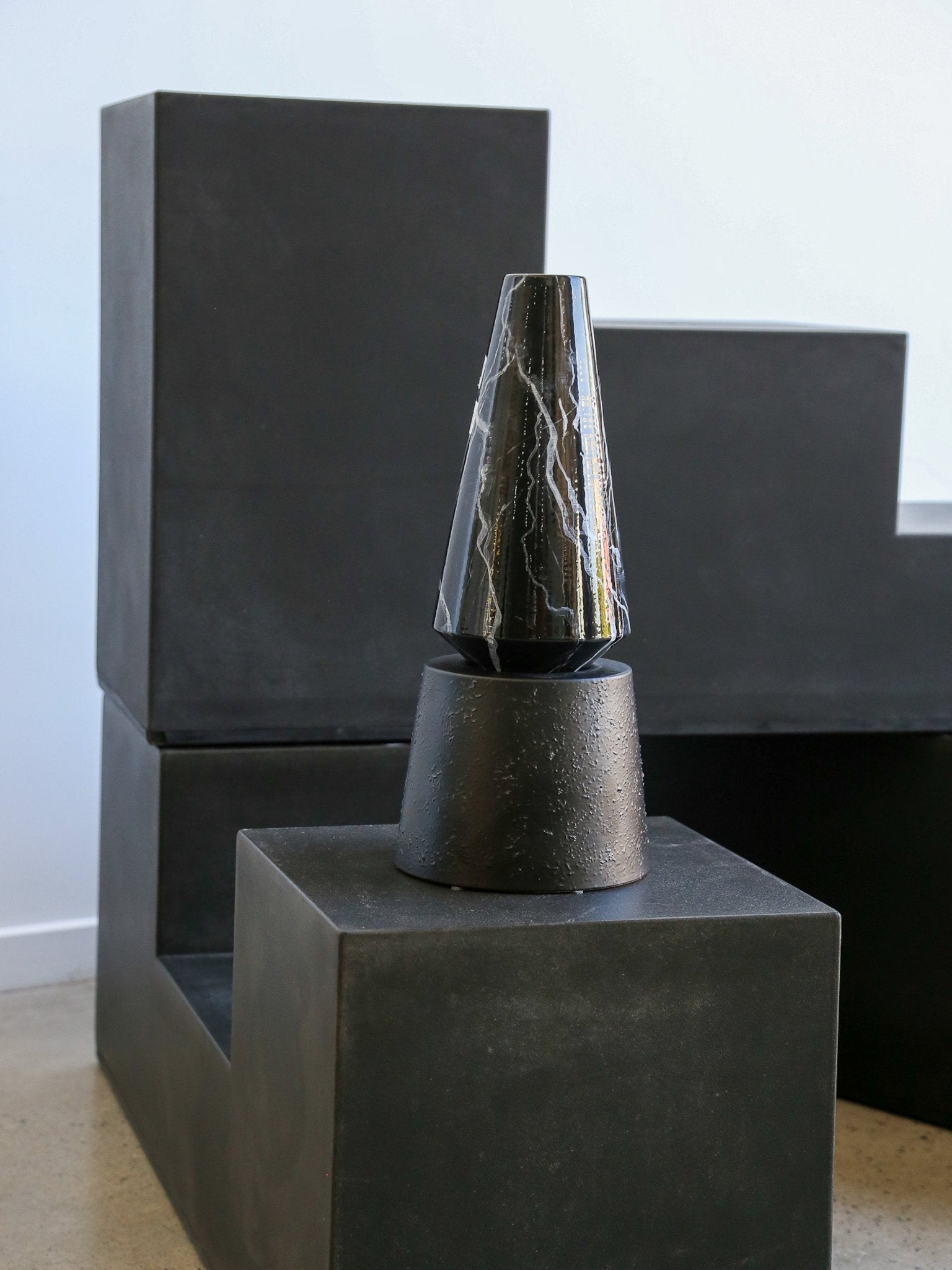 Dark stone sculpture on a pedestal with a plain background