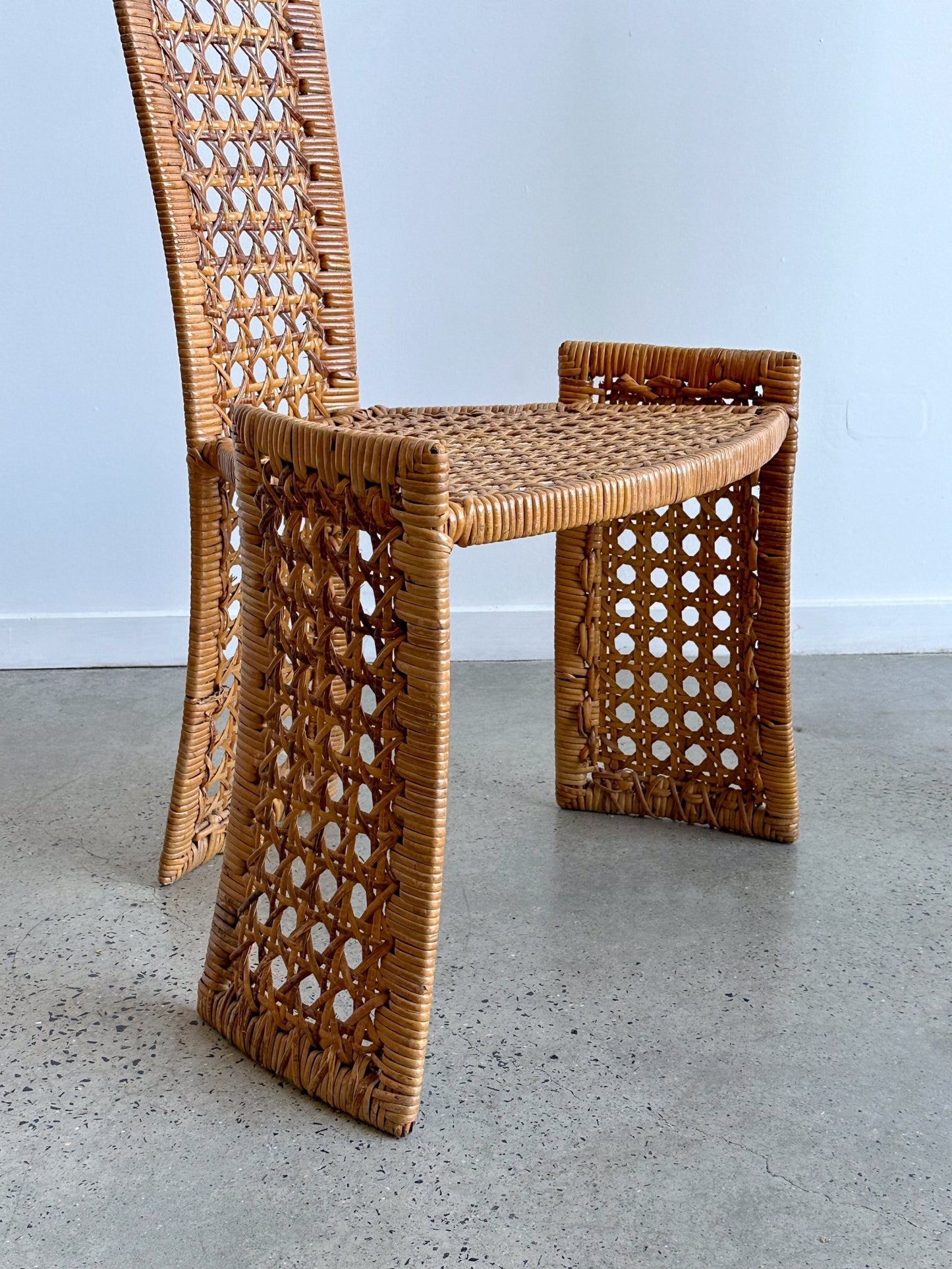 Woven wicker chair with a geometric design on a plain background
