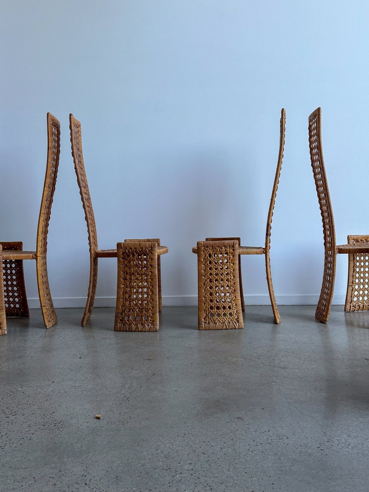 Wicker chairs and tables arranged against a light blue wall.