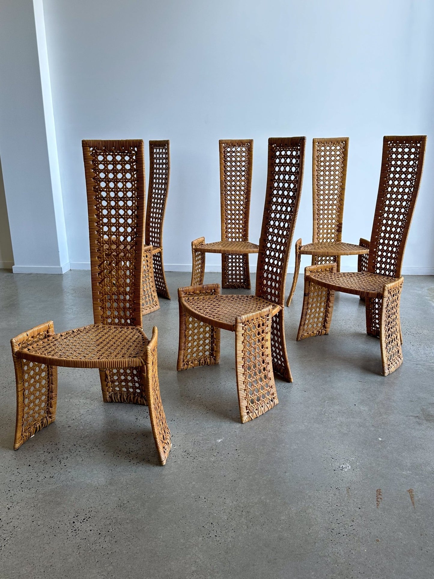 Set of wicker chairs arranged in a circle on a concrete floor.