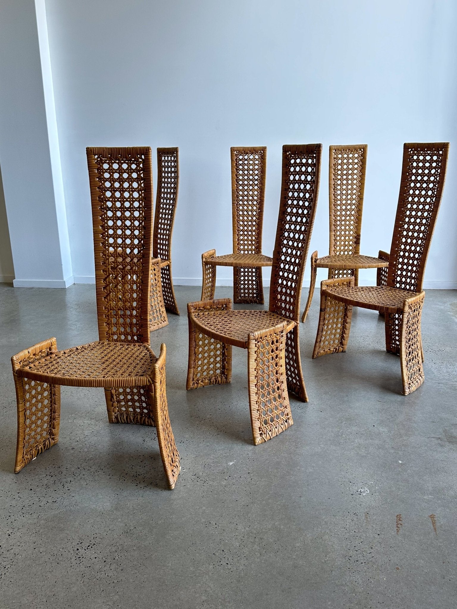 Set of wicker chairs arranged in a circle on a concrete floor.