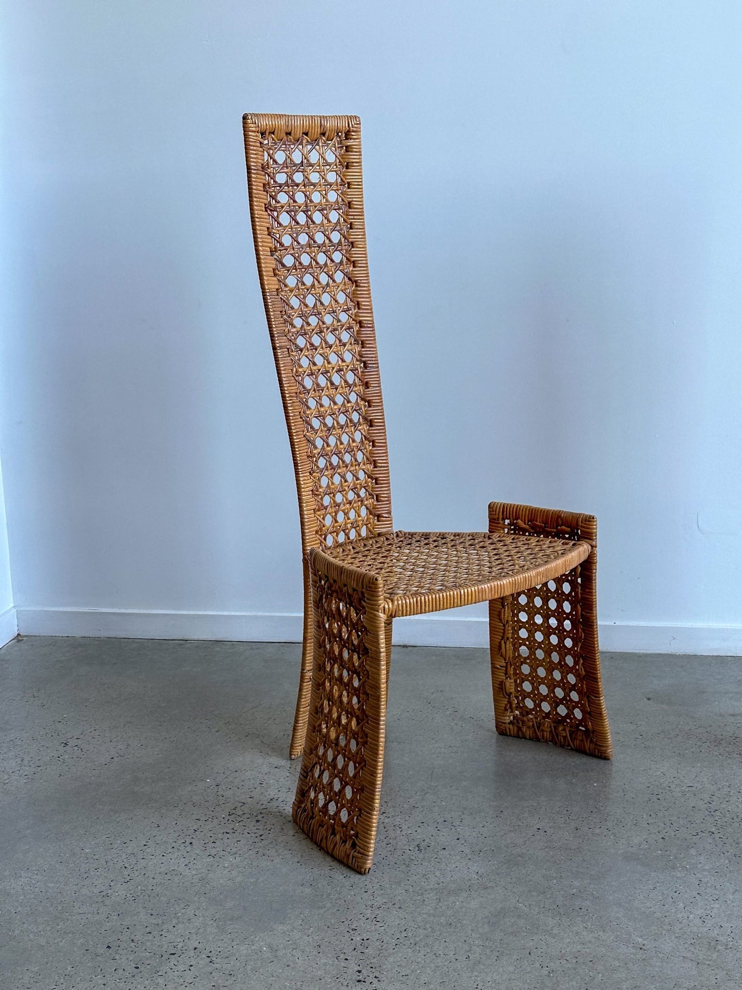 Woven chair with a geometric design on a plain floor and wall background