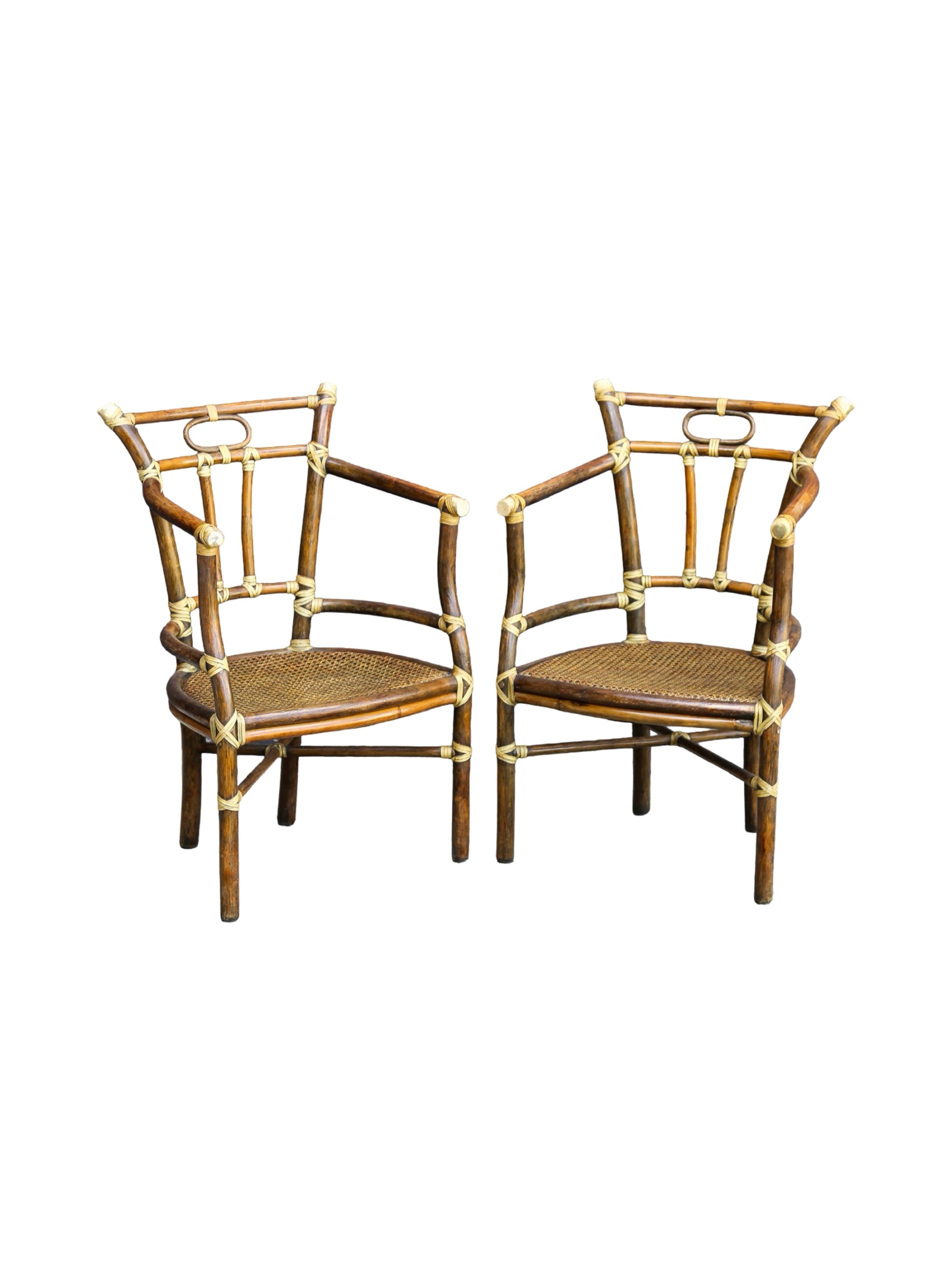 Two matching bamboo armchairs with woven cane seats and brass hardware, shown side by side on a plain white background.