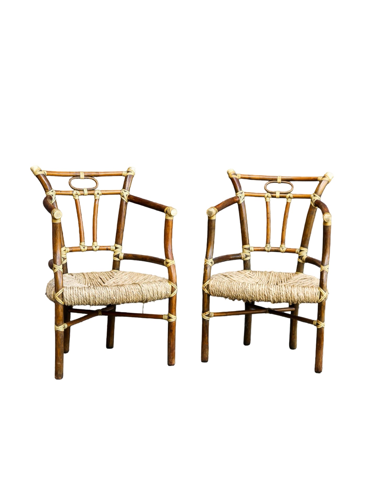 A pair of mid-century bamboo armchairs with woven straw seats and brass hardware, shown against a plain white background.