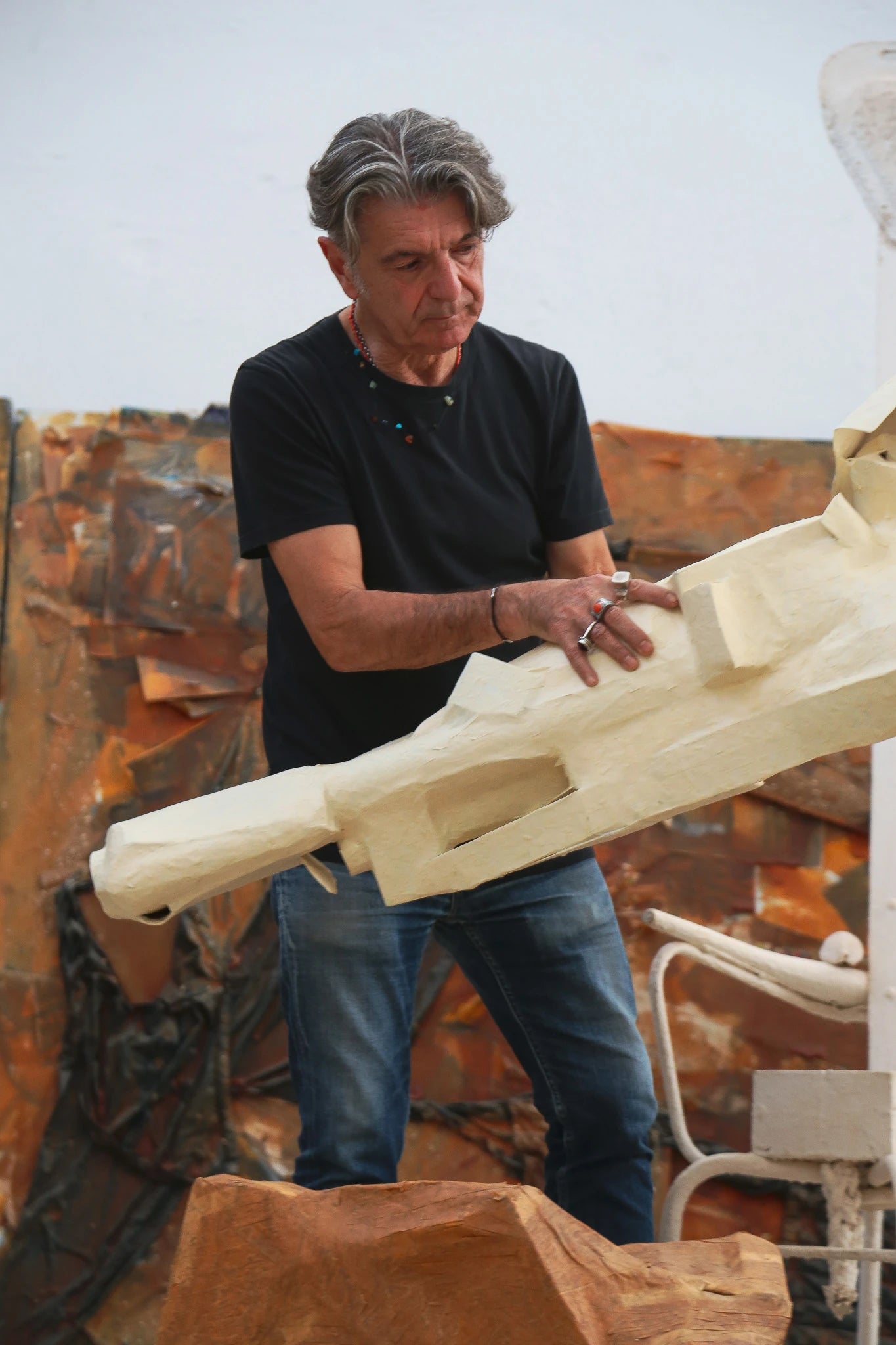 Man working on a wooden sculpture in an outdoor setting