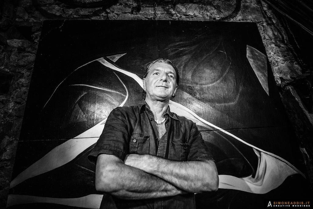 Man standing in front of an abstract painting with a textured wall background