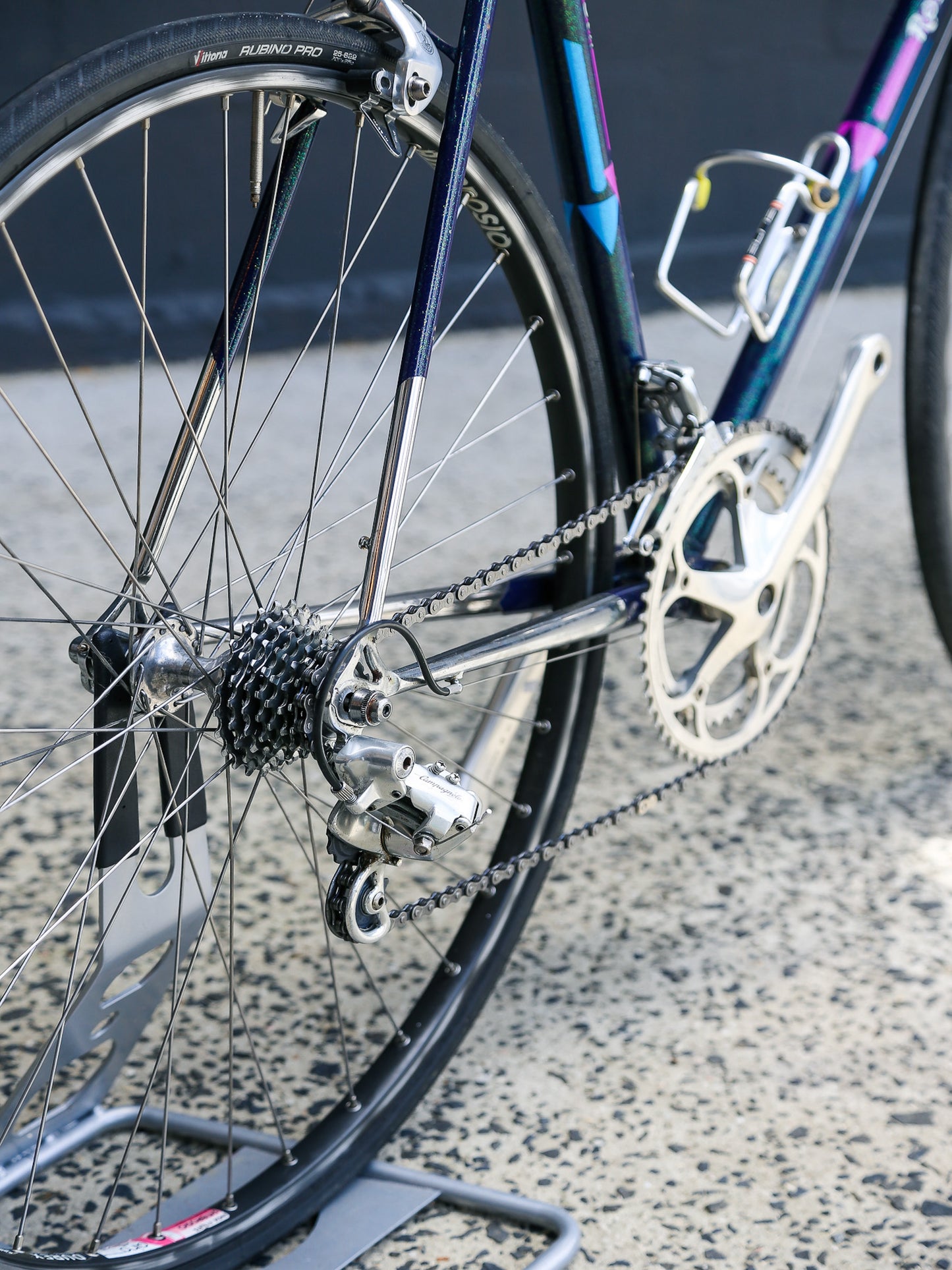 Close-up of a bicycle wheel and chain on a textured surface
