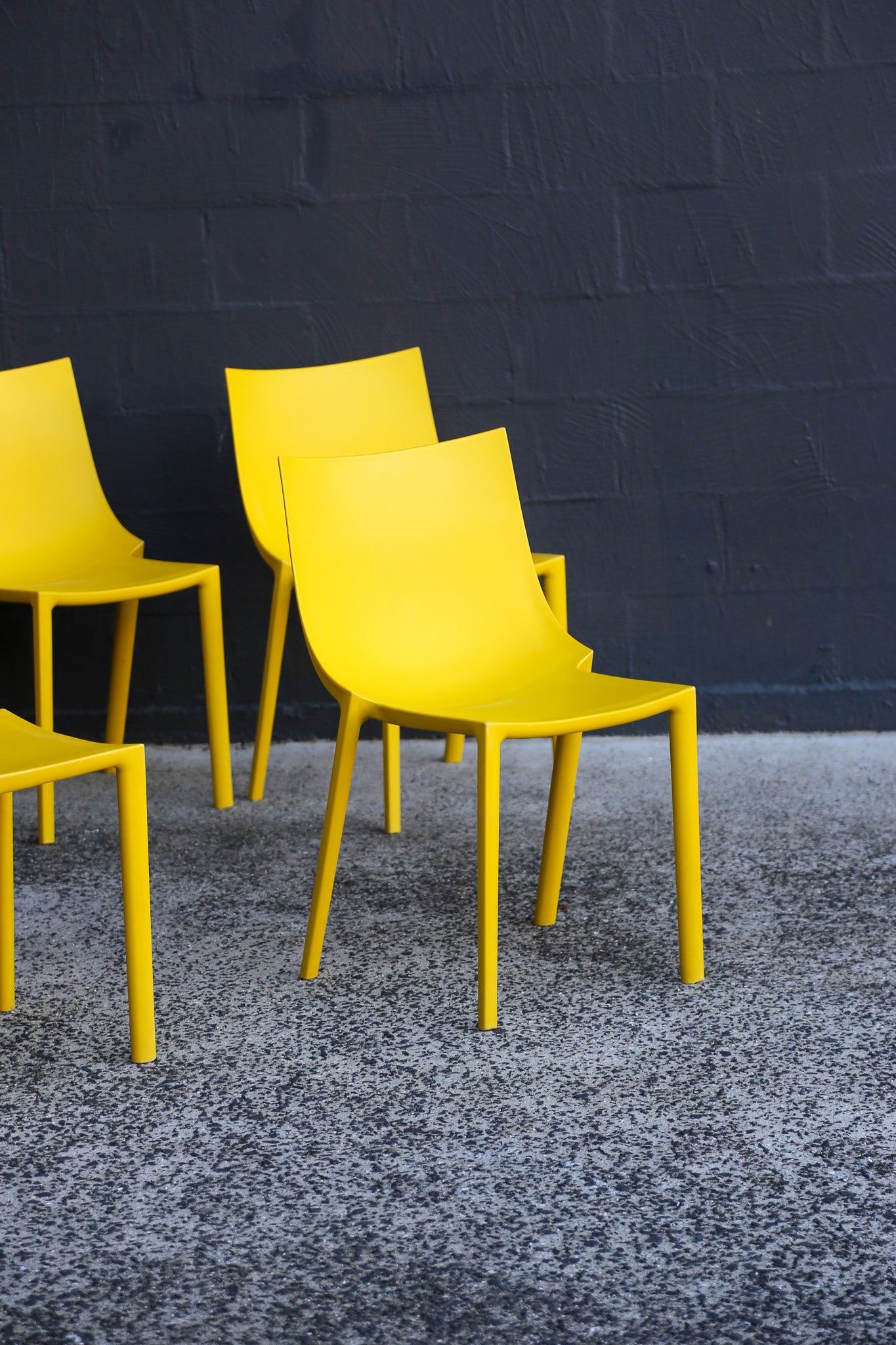 Yellow chairs against a dark blue brick wall.