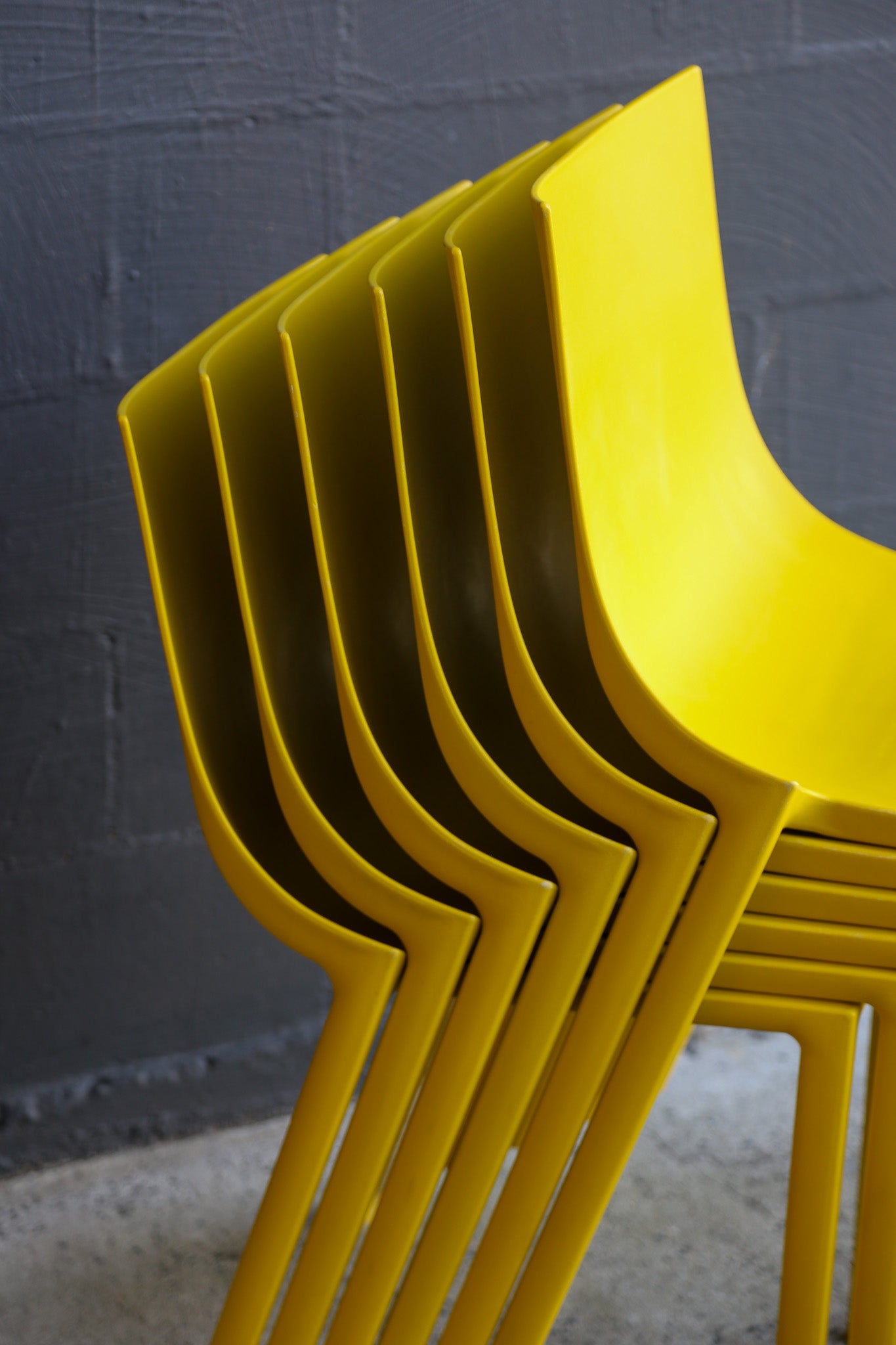 Stack of yellow chairs against a gray wall