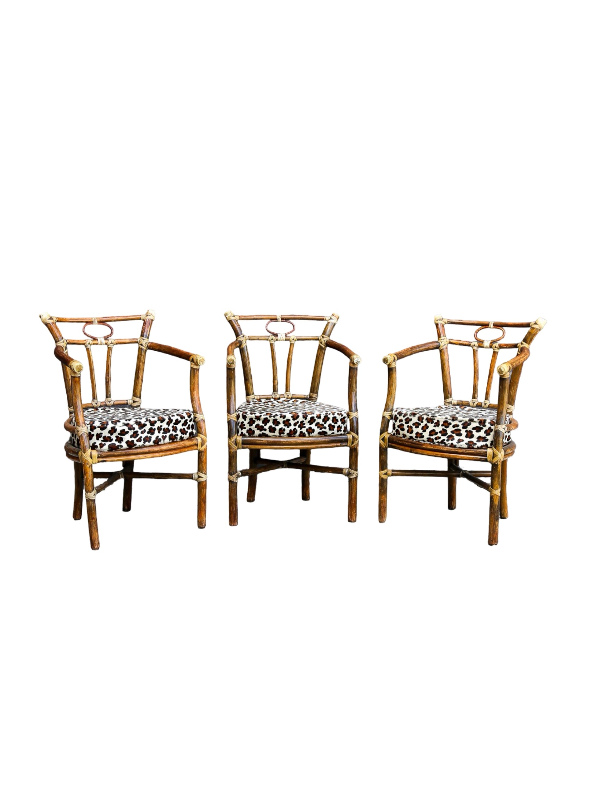Three matching bamboo armchairs with leopard-print upholstered seats, arranged side by side against a plain white background.