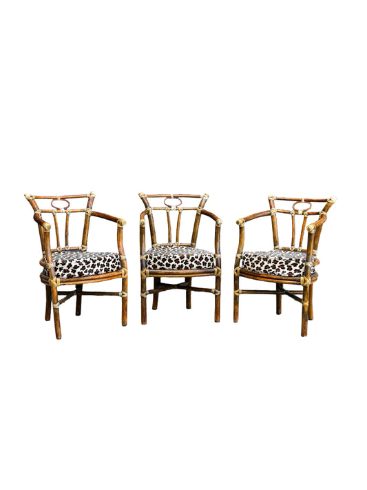 Three matching bamboo armchairs with leopard-print upholstered seats, arranged side by side against a plain white background.