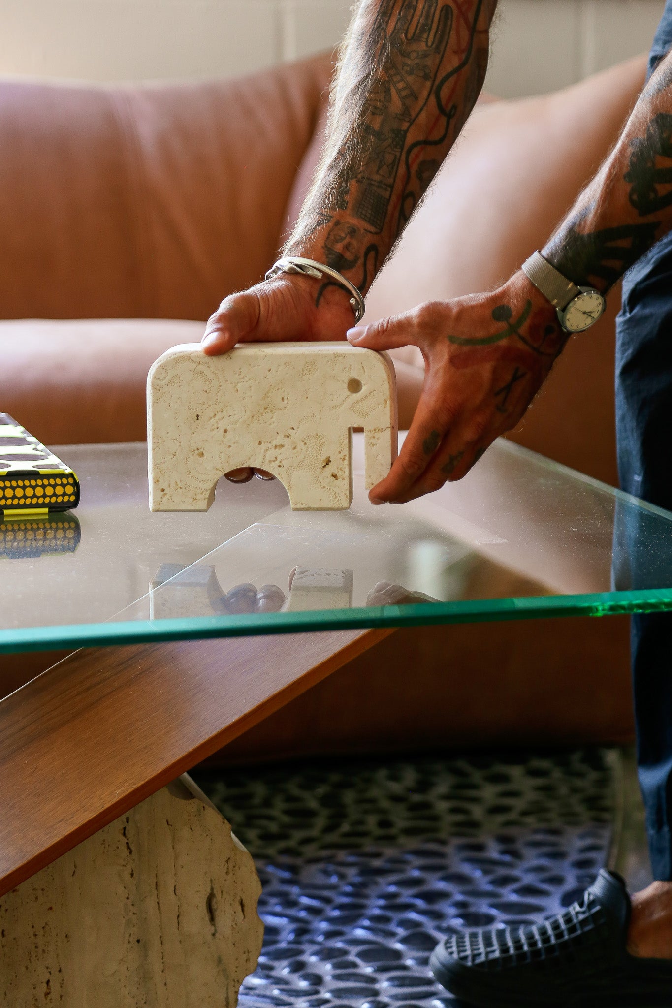 Person holding a small stone elephant sculpture on a glass table