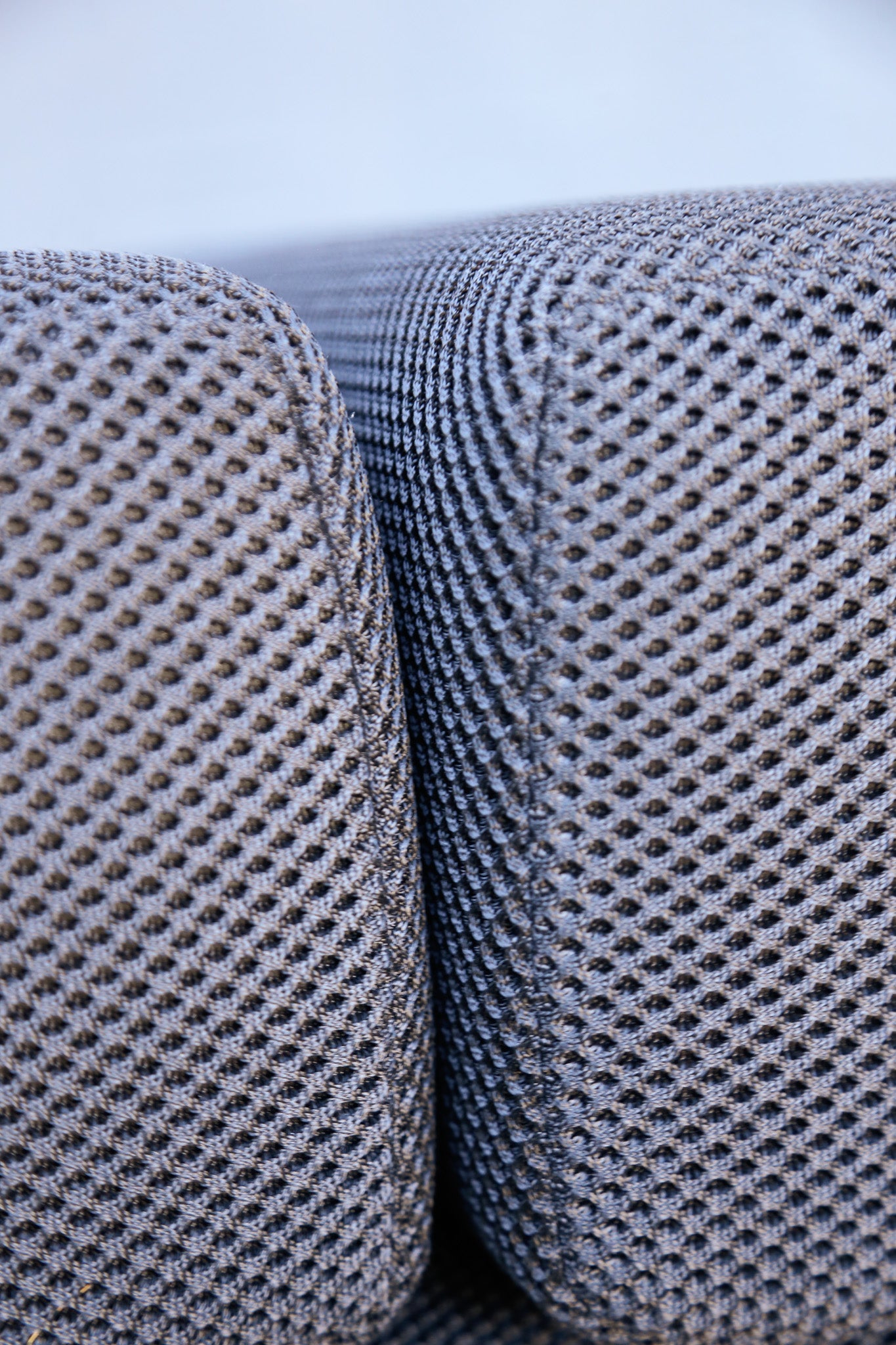 Close-up of textured black mesh fabric upholstery on a cushion, showing the woven pattern and soft edges.