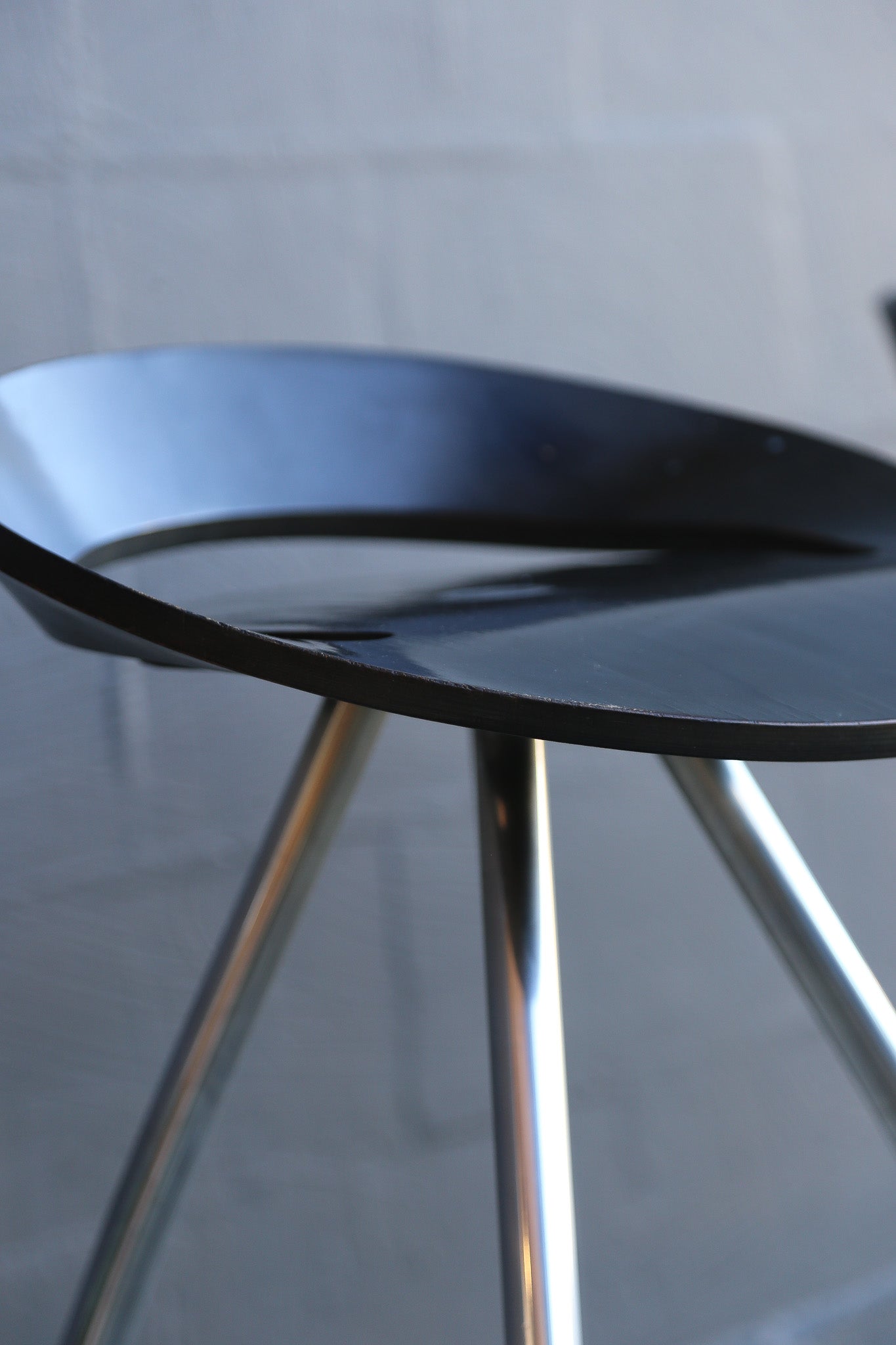 1990s black chair with chrome legs against a gray tiled wall