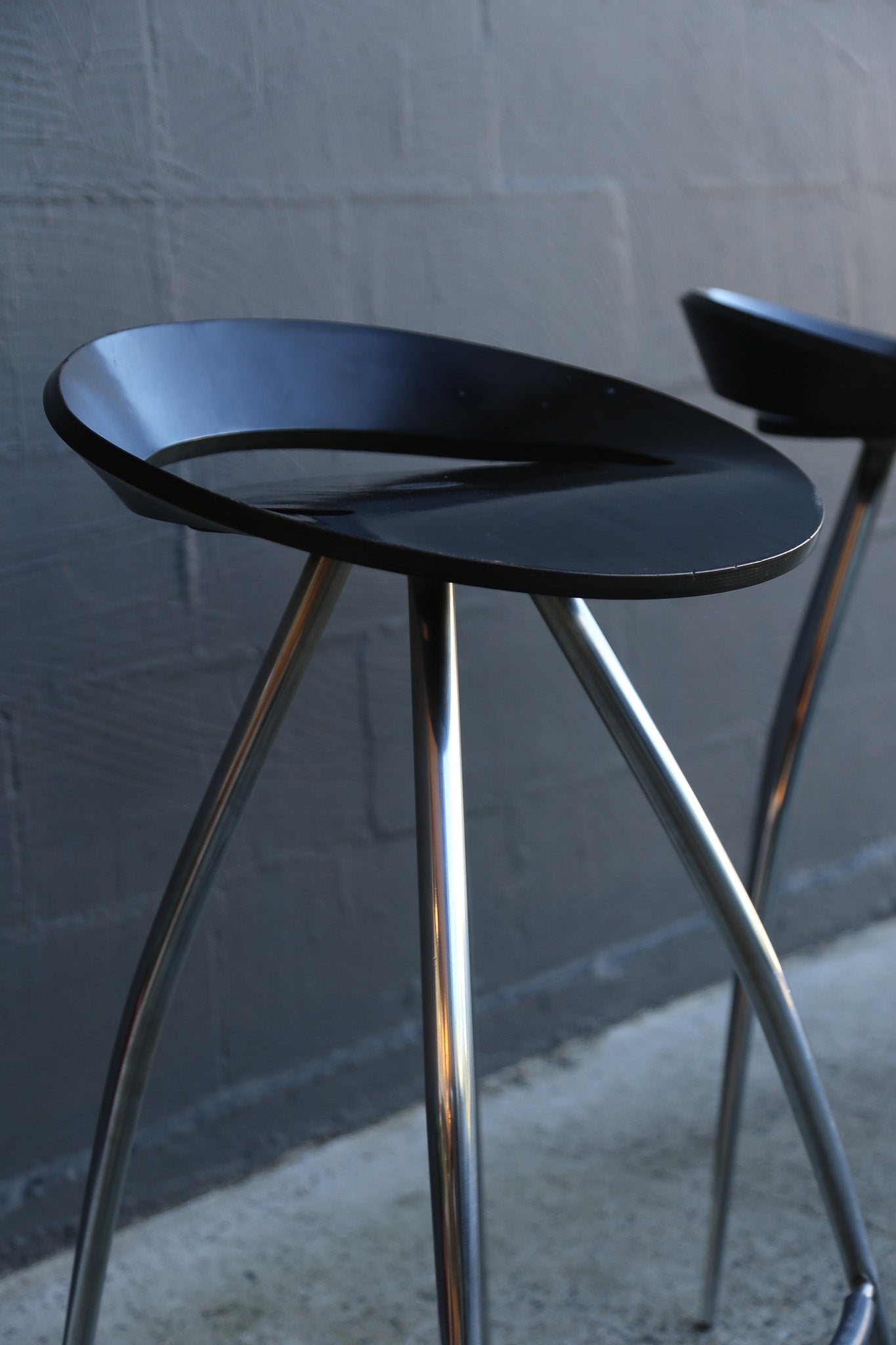 1990s black stool with metal legs against a textured wall.