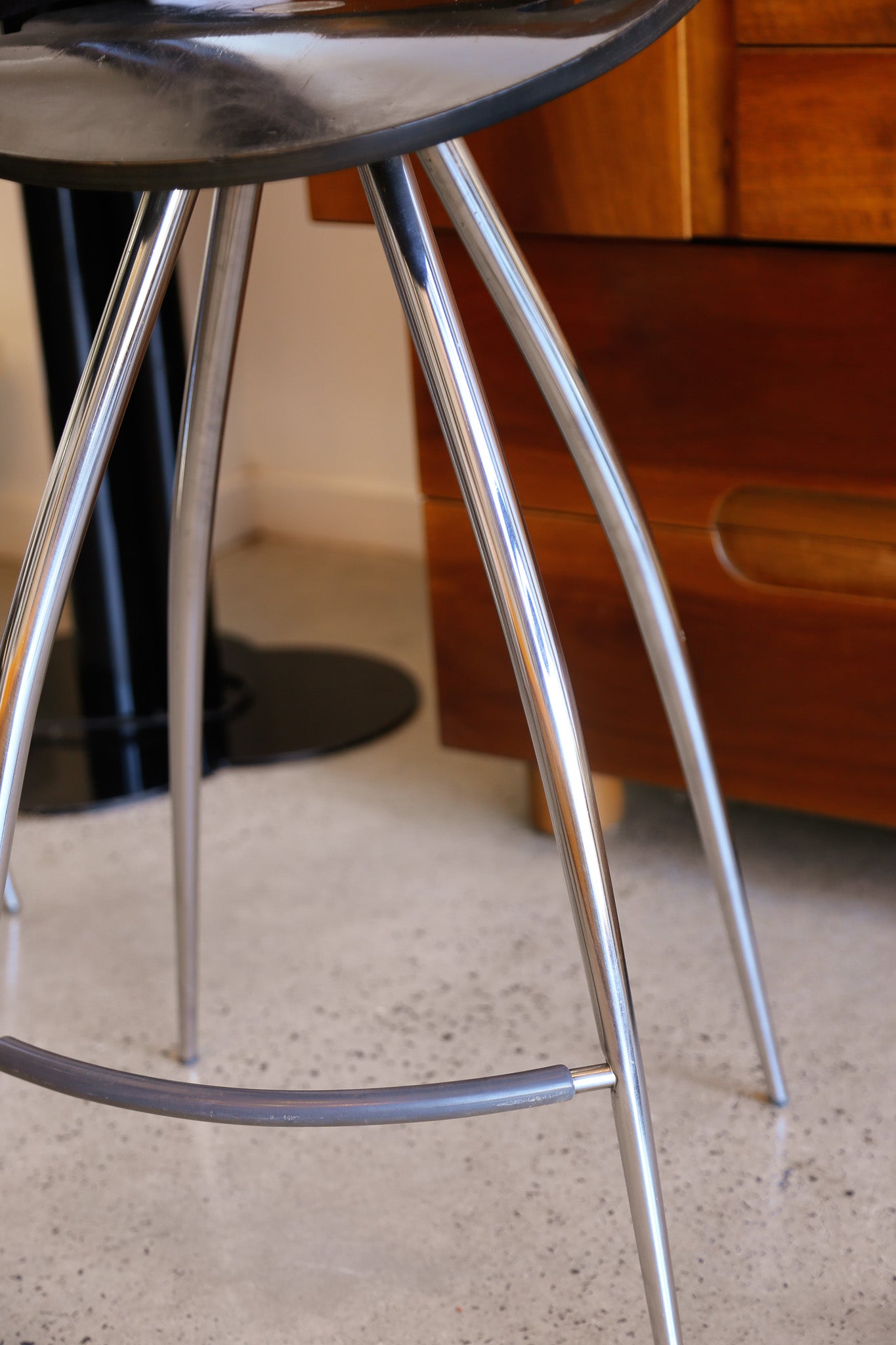 Metal stool with a black seat on a concrete floor