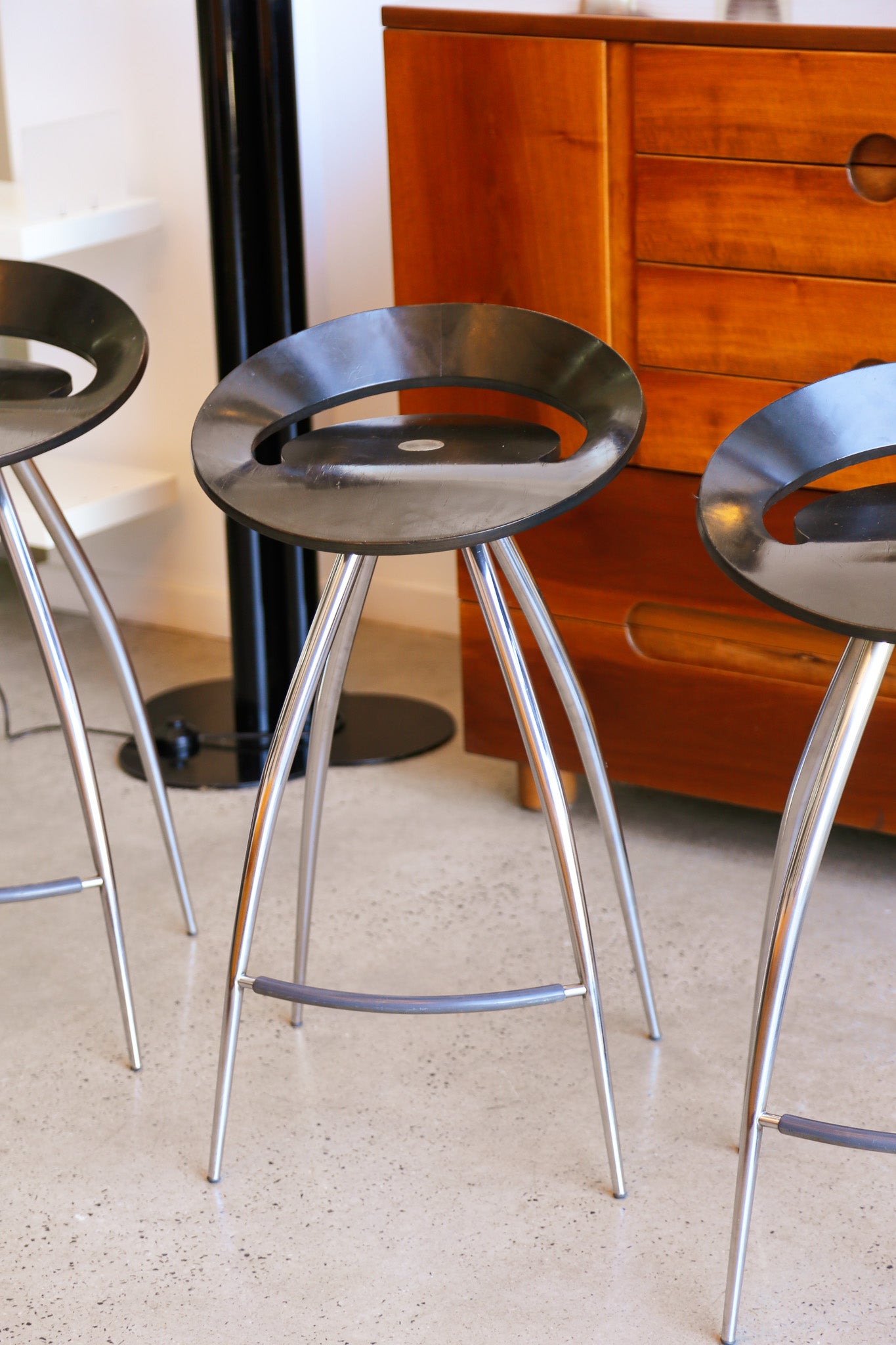 bar stools with metal legs and black seats in a room with wooden furniture.