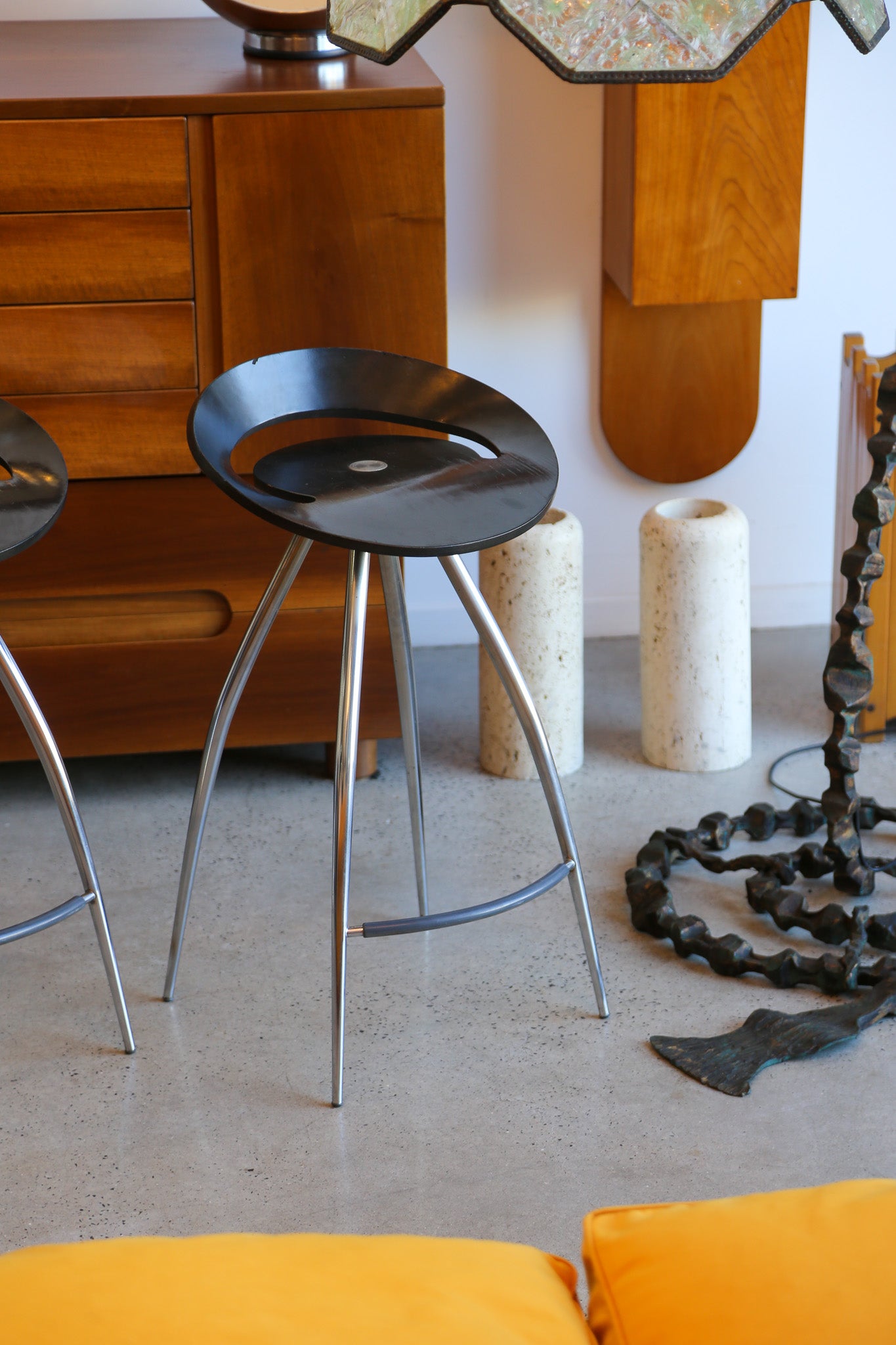 black stool with metal legs in a room with wooden furniture and decorative items.